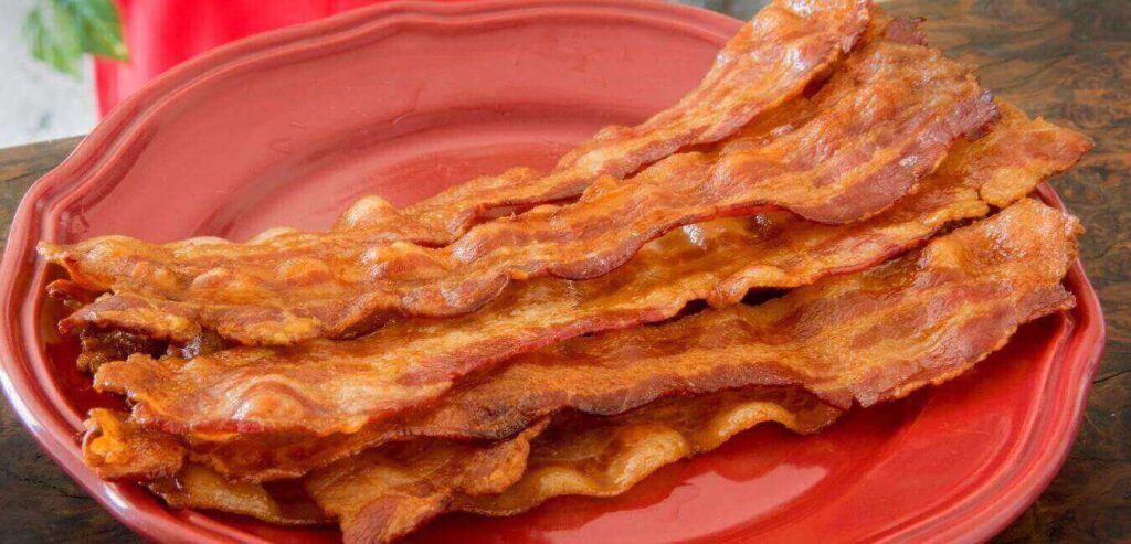 Crispy bacon on a red plate sitting on the table