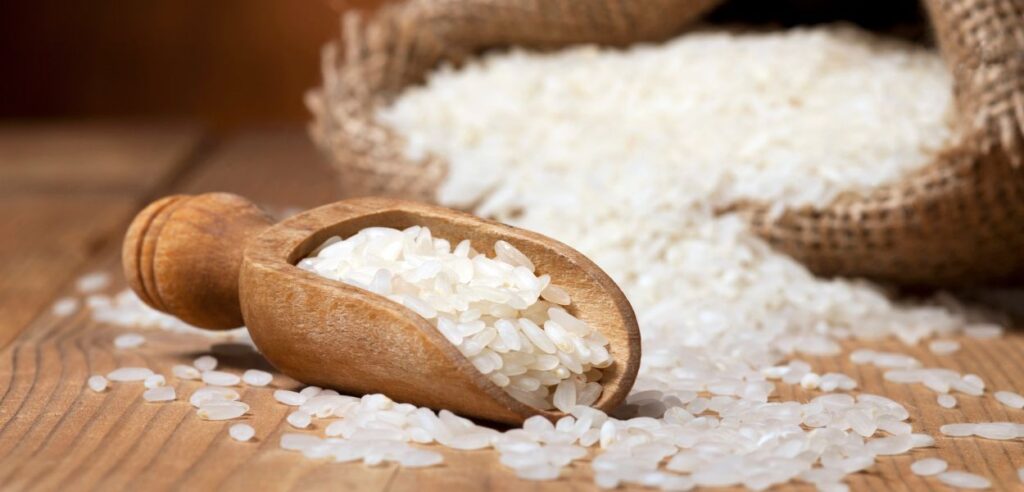 white rice in a basket and wooden scoop